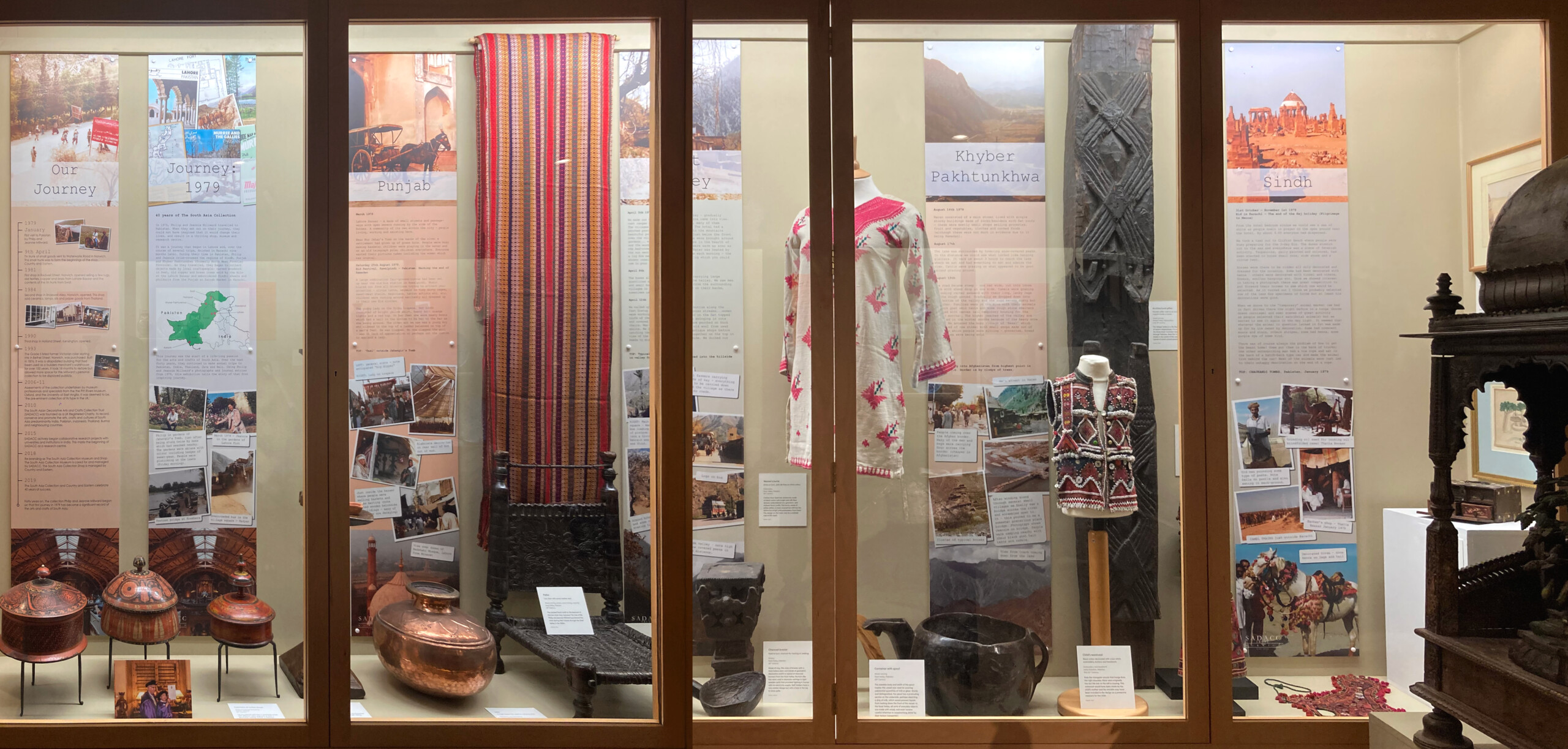 This shows the 'Journey: 1979' case in full with several large information boards with images and lots of objects from textiles to wooden items throughout.