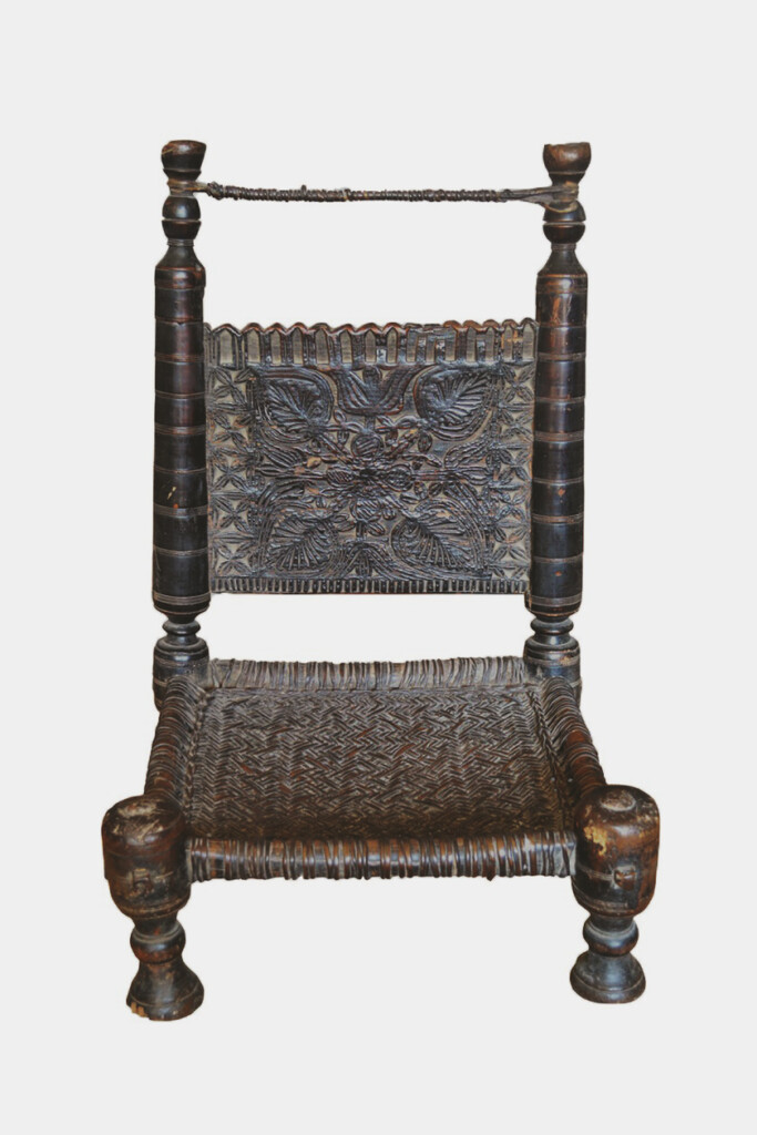 A low chair made of dark wood with intricate woven seat and back.