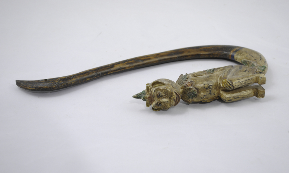 This shows a wooden hook on it's side with a carved monkey figure at the wide end.