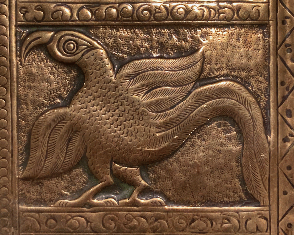 This image shows a section of the tray. It is a stylised side profile of a parrot facing left. It has its wings spread and a long tail and large beakl. There is an ornate border around this.