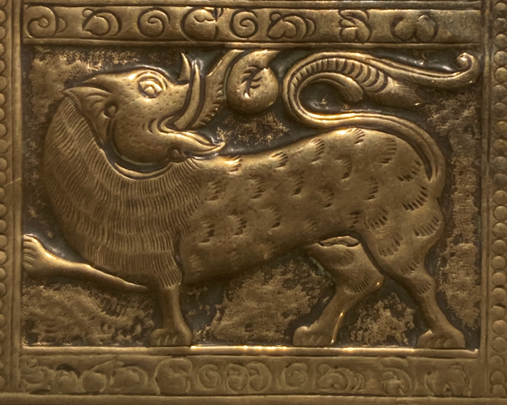 This shows part of the tray. It is a stylised elephant headed lion. It has an ornate border around this symbol.