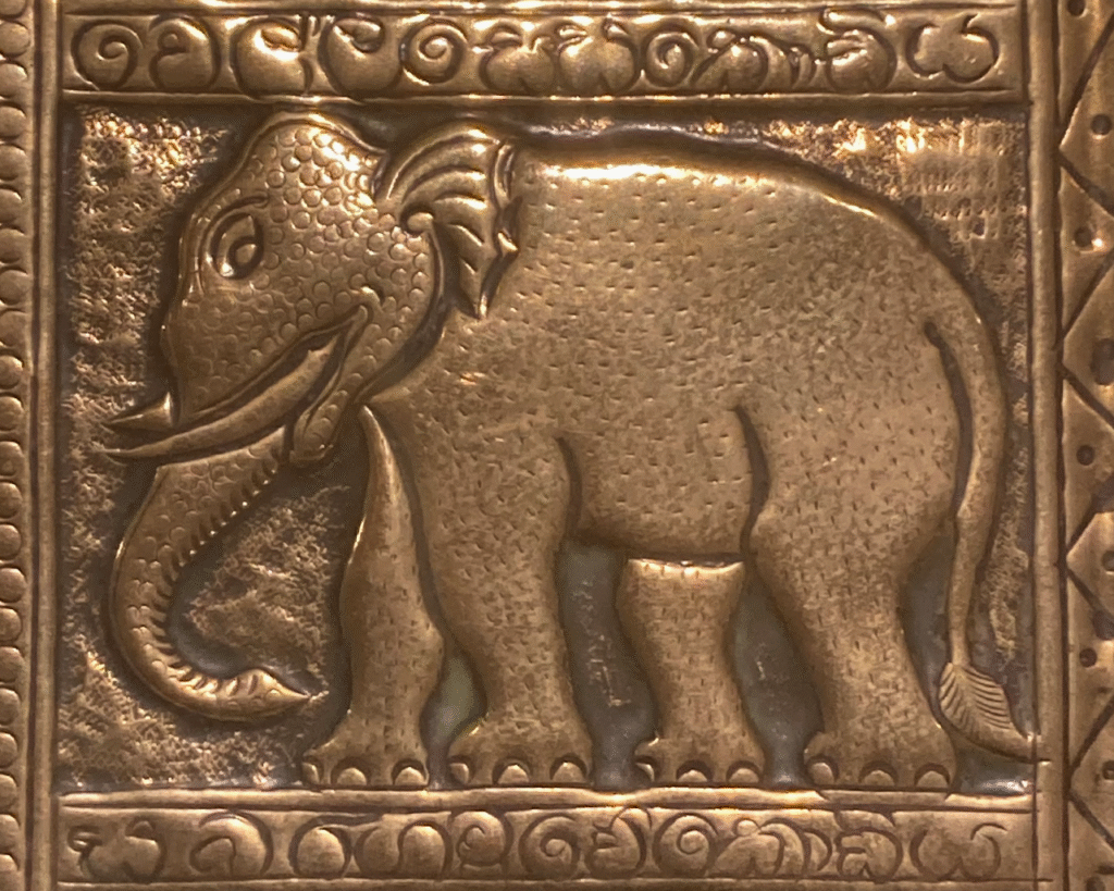 A close up of a section of the tray. It shows a stylised side profile of an elepohant facing left. It's trunk is facing downwards. There is an ornate border around this.