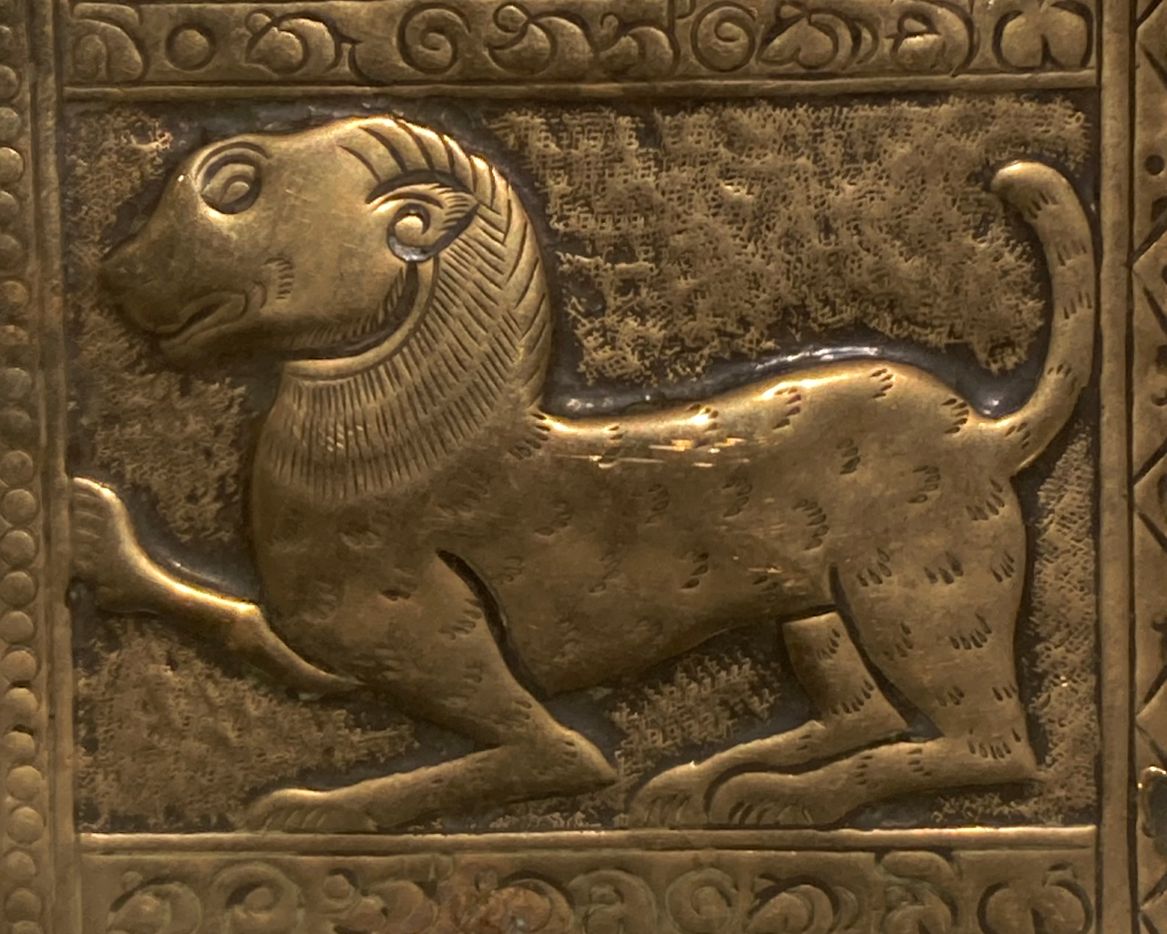 This image shows part of the tray. It is a stylised side profile of a bear facing left. It has three feet on theground and one front paw is raised and it's tail is raised which looks like a cats tail in shape. It has detailing of fur throughout. There is an ornate border around this.