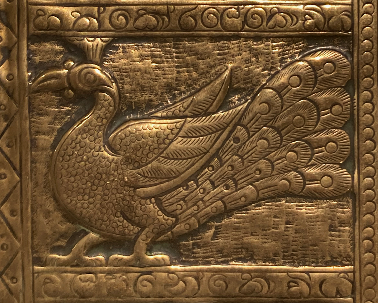 This shows part of the tray, it is a side profile of a stylised peacock with a detailed tail. There is an ornate border around this.